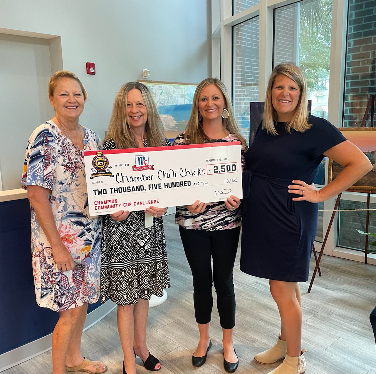 chamber team smiles while holding big check for $2,500