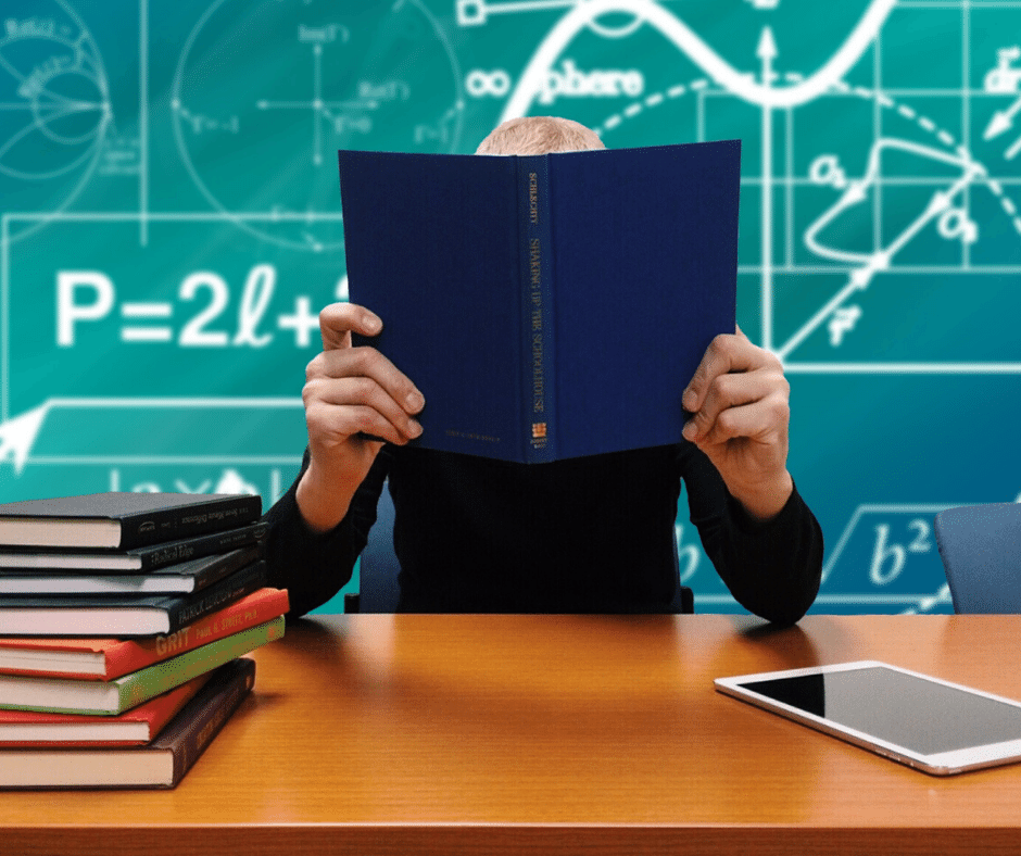 man holding book next to stack of books