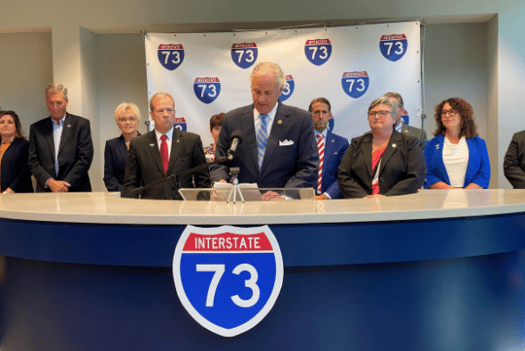 S.C. Gov Henry McMaster stands at podium surrounded by people