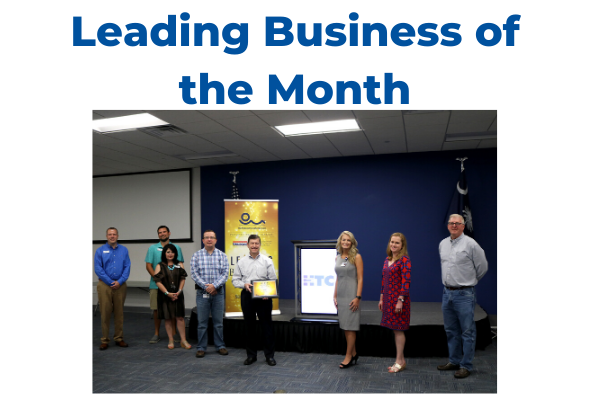 people standing in front of banner reading Leading Business of the Month