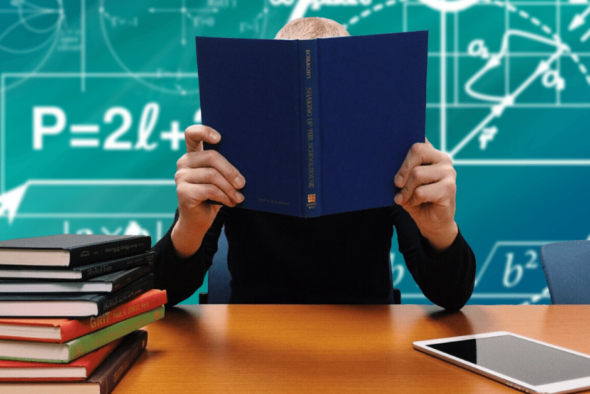 photo of man reading book next to stack of books