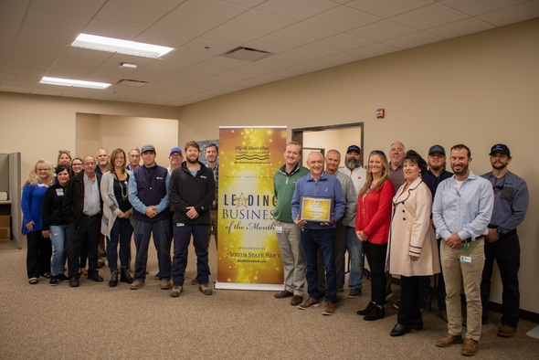 Dominion Energy staff and chamber ambassadors smile for photo in front of gold banner.