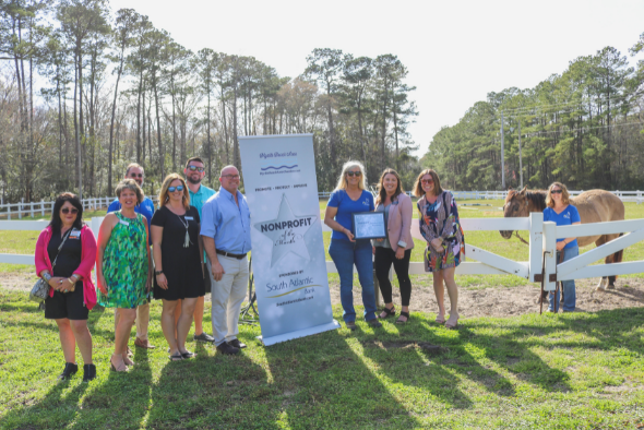 Barnabas Horse Foundation staff stand in grass with brown horse